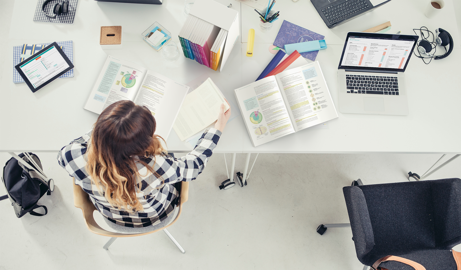 medical student studying at a messy desk with books open and laptop