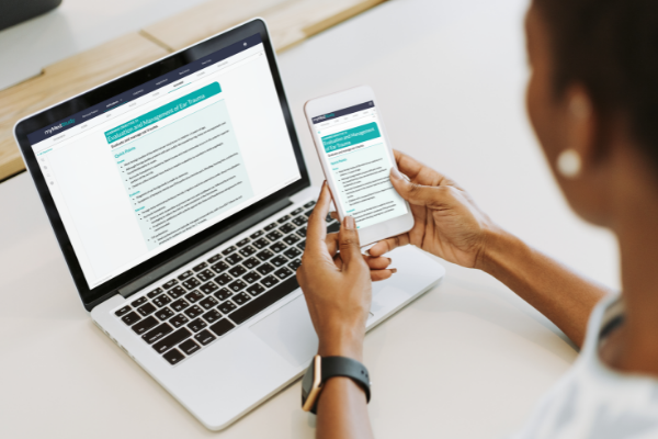 Person on phone reading the QuickREF with a laptop in the background also showing the QuickREF